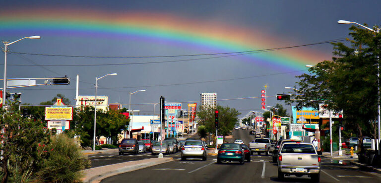 Cars drive under a rainbow on Route 66 in Albuquerque, NM.