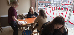 A waitress takes orders from two women by a window in McQueals Bistro