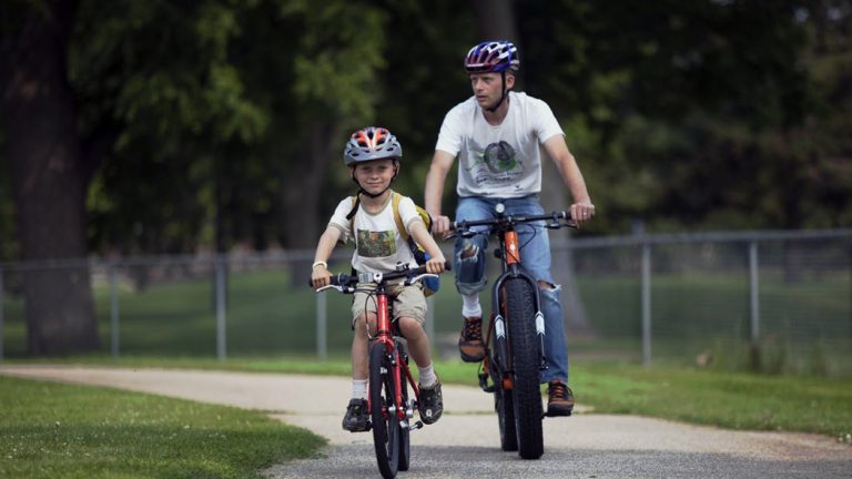 A boy and man bike on a trail in Rochester, MN