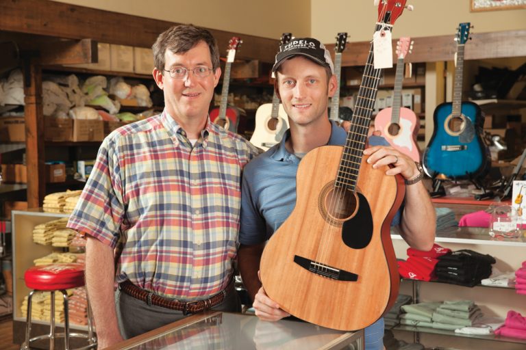 George Booth II and George Booth III with a guitar at Tupelo Hardware.