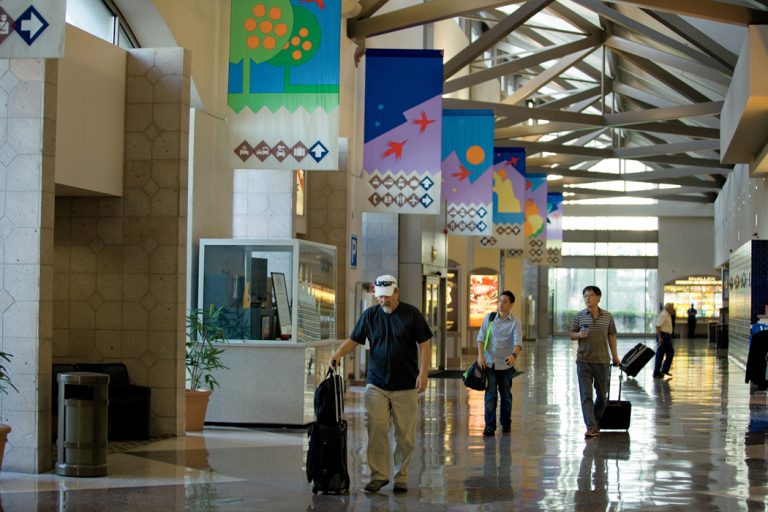 Travelers walk through the McAllen Airport with luggage.