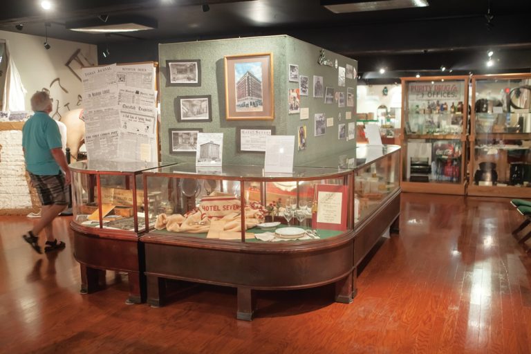 A man walks past a glass case containing exhibits in the Three Rivers Museum.