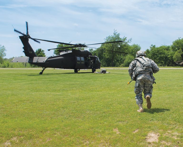 A soldier runs towards a helicopter.