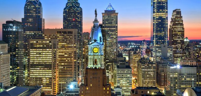Philadelphia Skyline at dusk, which a blue sky on top and orange on bottom.