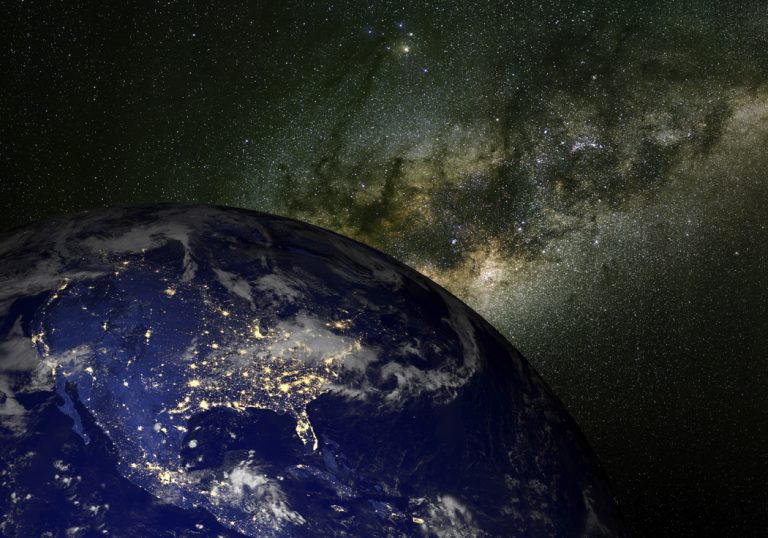 The United States as seen from space with the Milky Way Galaxy behind a dark blue earth.