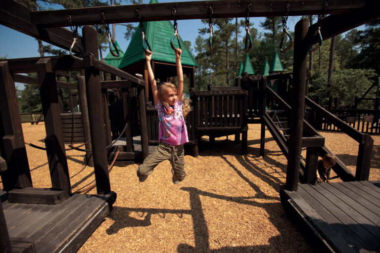 A girl swings on the monkey bars at Treehouse Playground in Fairview