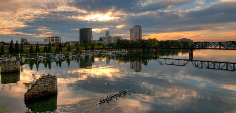A crew team paddles across the river as the sun rises over the city of Augusta, GA.