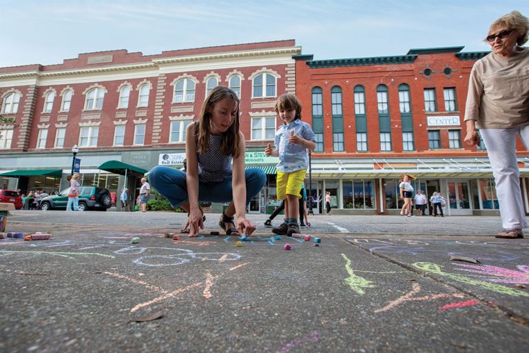 Thomas Cooper draws on the sidewalk with her mother Diana during an art walk event in downtown Elizabeth City, North Carolina.