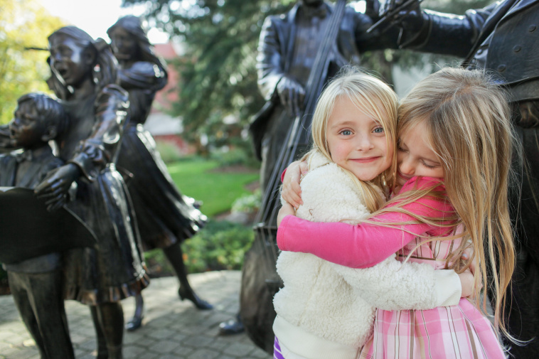 Two little girls pose next to a statue in Downtown Holland, Michigan.