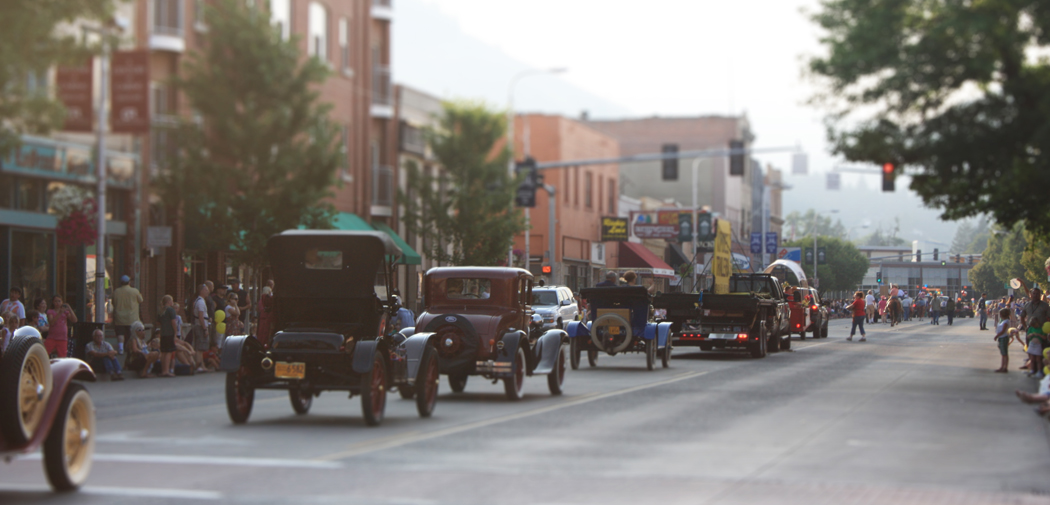 Old cars, Model Ts and Buicks, drive through downtown during a parade.