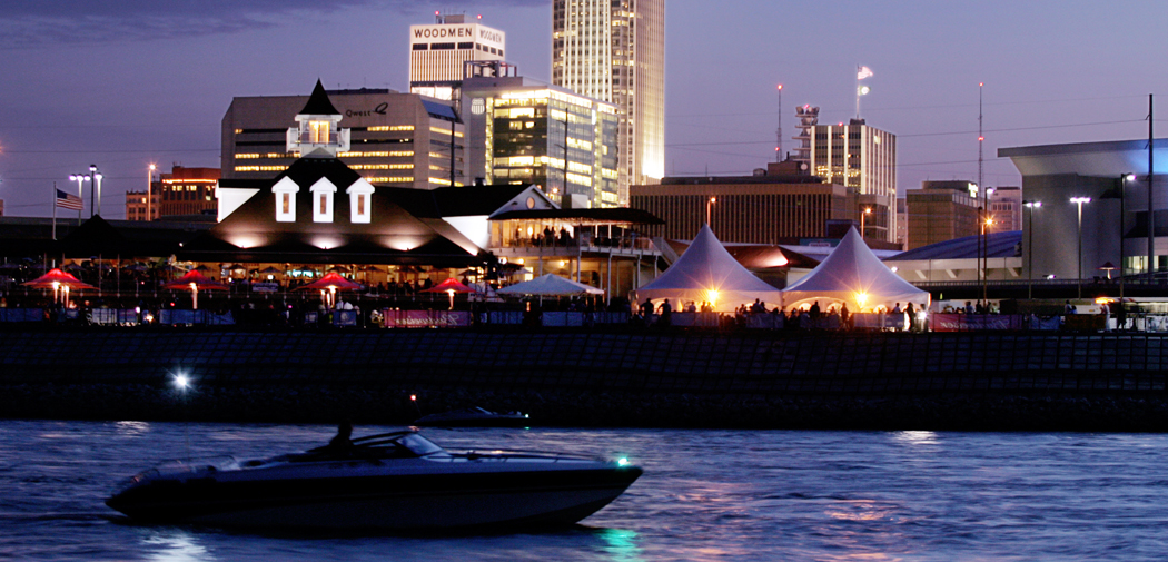 View of the Omaha downtown skyline at night with a boat in the water.