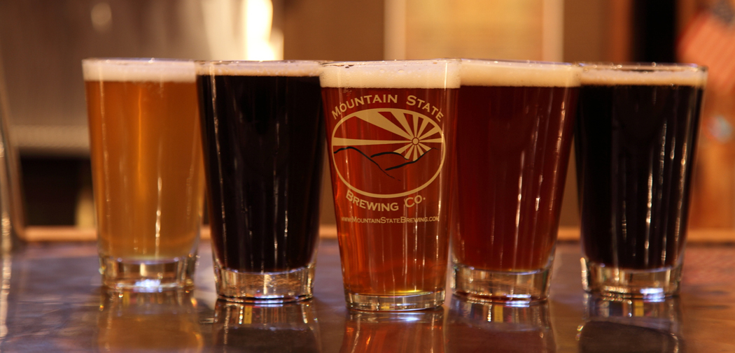 Pint glasses displayed on the bar with different beers at Mountain State Brewing Co.