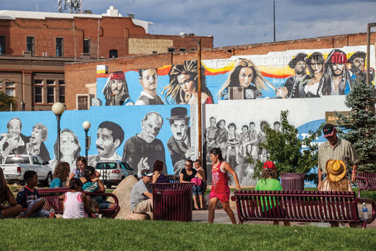 Families play in the park across the street from the new mural painted next to Bingo Burger in downtown Pueblo, Colorado.