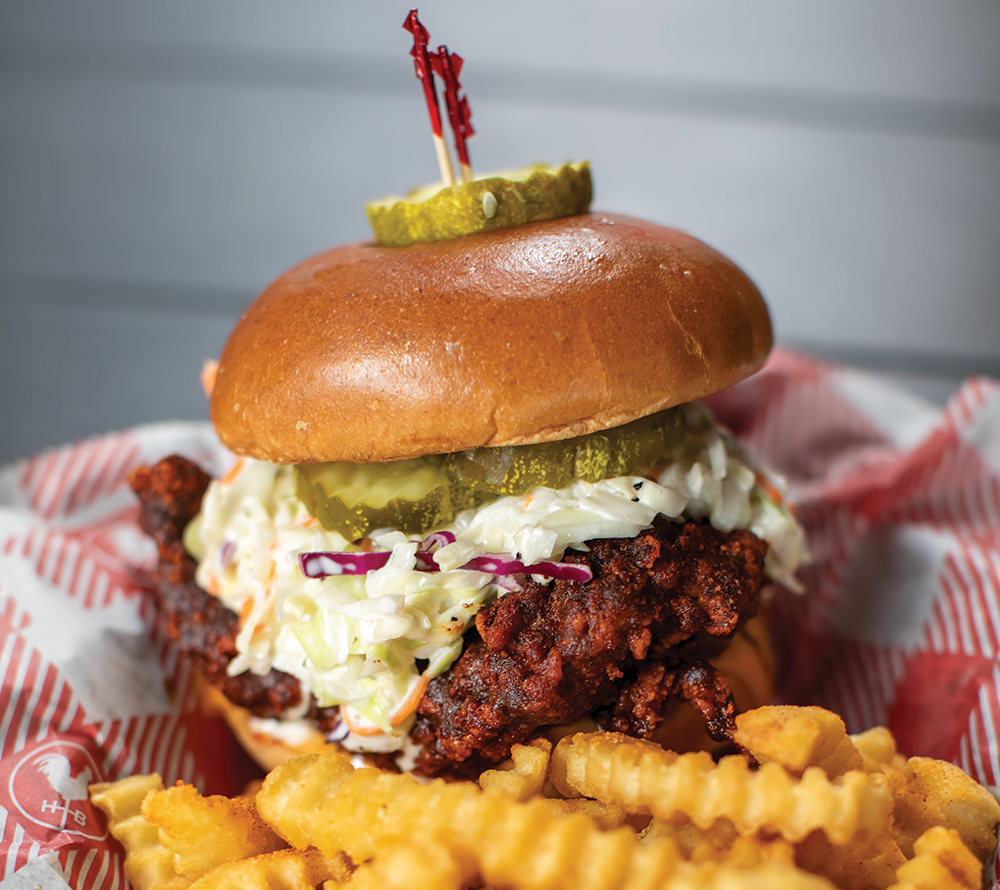Closeup of a Nashville hot chicken sandwich with coleslaw and french fries
