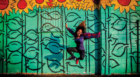 Woman jumping in front of a mural in Nashville