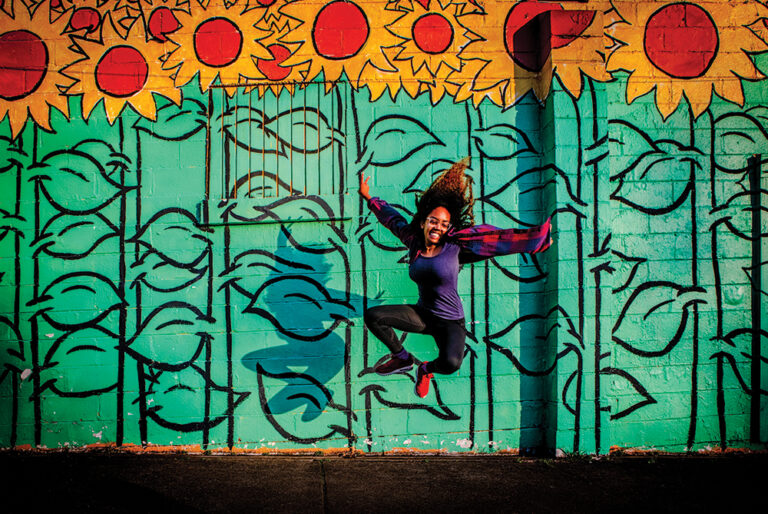 Woman jumping in front of a mural in Nashville