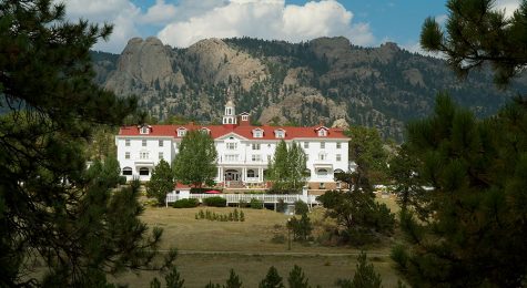 Exterior shot of the Stanley Hotel between the trees in Estes Park CO