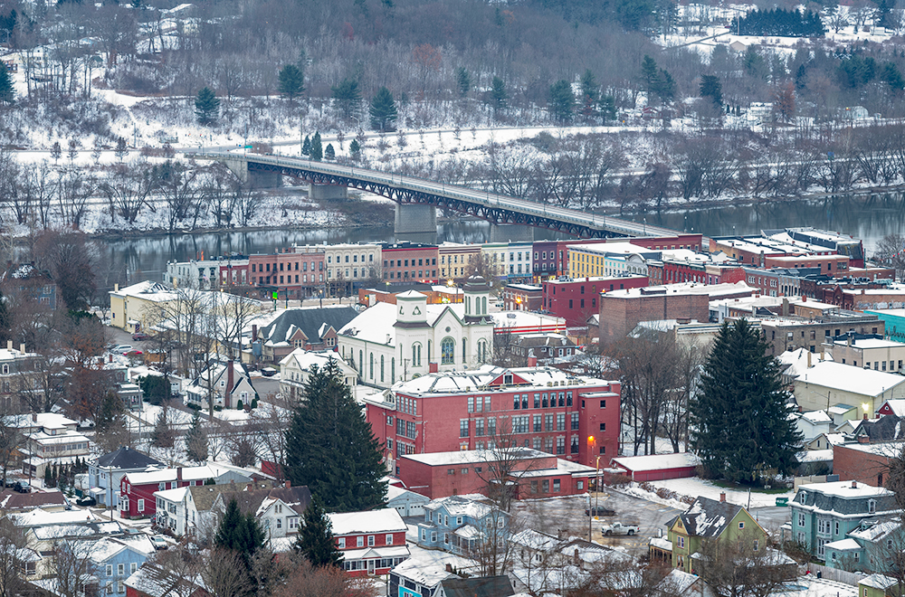 Owego is a small village in New York State, located along the Susquehanna River, photographed from the top of a hill during a winter morning with fresh snow on rooftops.