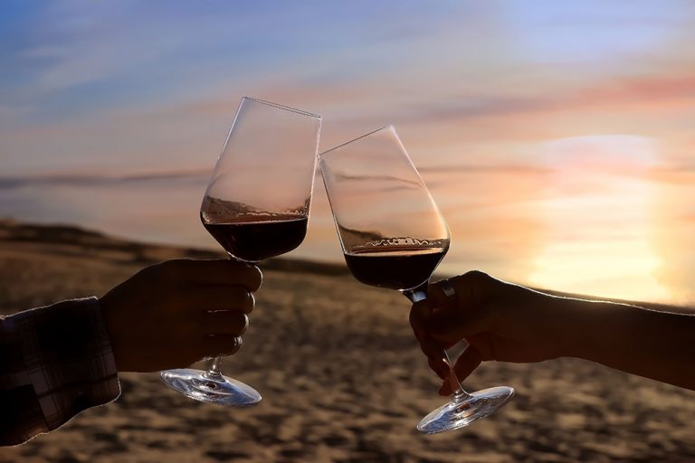 Selective focus of couple hands which Couple drinking wine in sea restaurant on the beach background