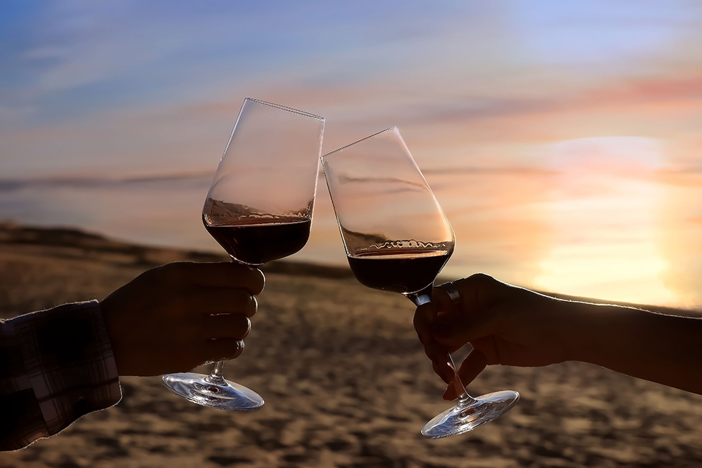 Selective focus of couple hands which Couple drinking wine in sea restaurant on the beach background