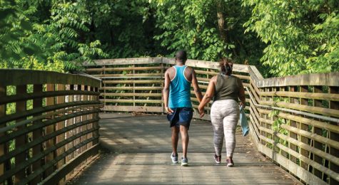 A couple walks across a wooden bridge over the West Fork Stones River on the greenway trail in Murfreesboro, Tennessee.
