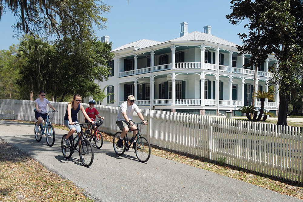 A family of cyclists ride along a path outside of DeBary Hall in DeLand, FL (Greater Daytona Region).
