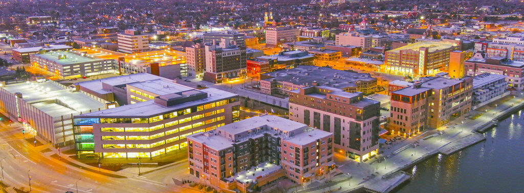 An aerial view of downtown Green Bay, WI, at twilight. Living in Green Bay, you'll have access to a diverse dining scene, arts and culture, plus plentiful parks and outdoor activities.