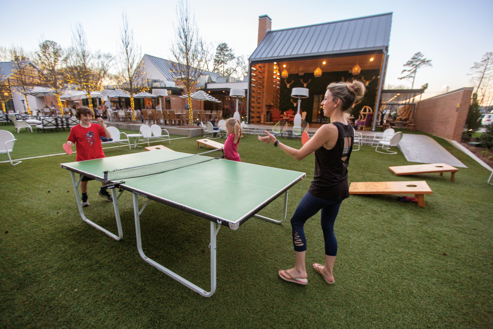 Families play table tennis outdoors on the lawn at The Grove Kitchen & Gardens;