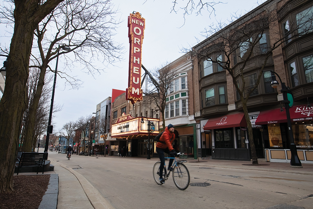 People bike in front of the Orpheum Theater in Madison.