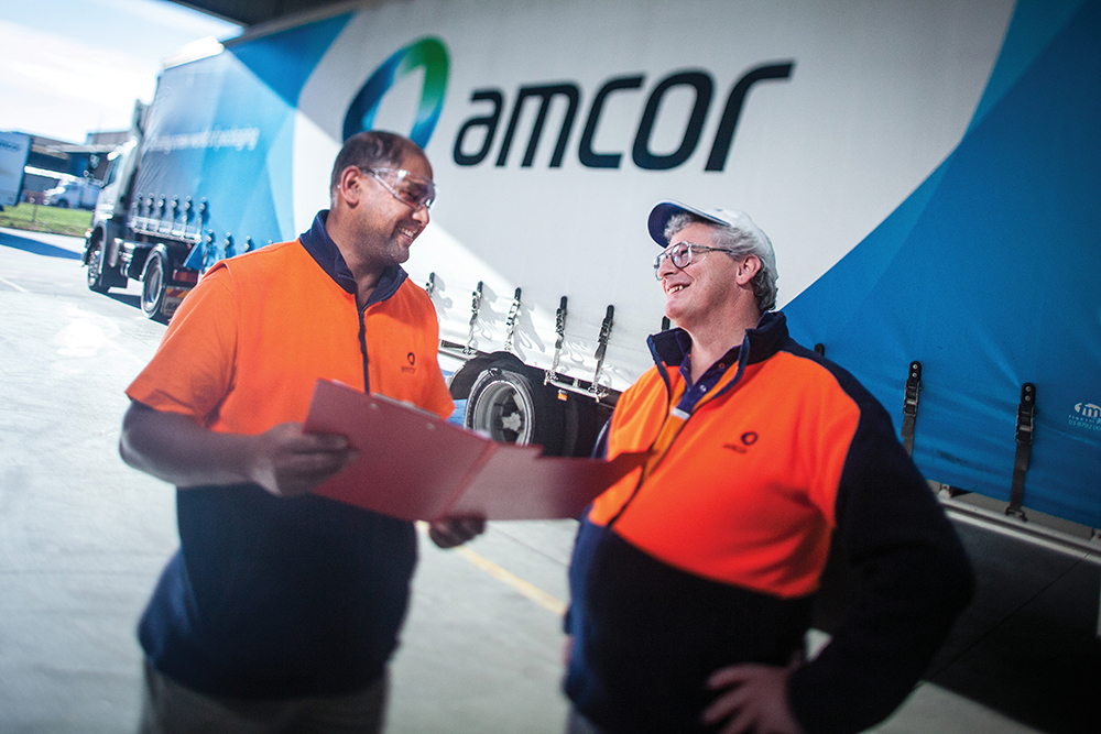 Two Amcor employees review papers. The business is located in the Greater Madison Region.