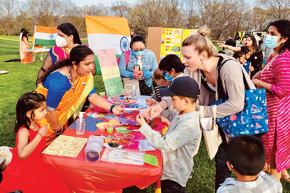 Photo of children and their parents gathering around an arts and crafts booth at the Quincy Multicultural Festival in Quincy, MA.