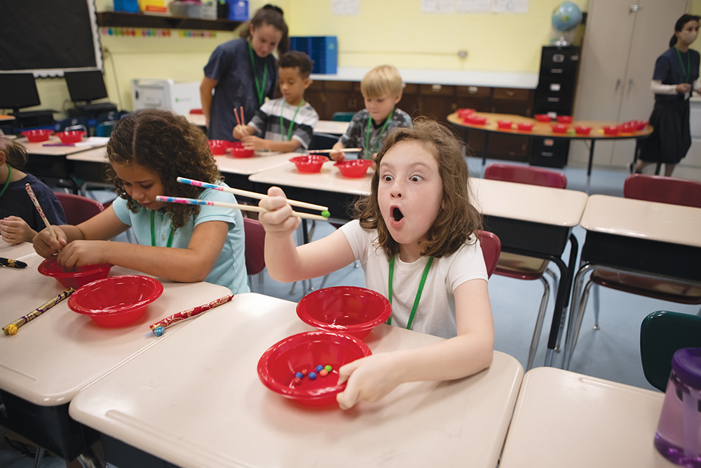 Elizabeth Gates, right, reacts to picking up a Skittle while learning to use chopsticks with Charlotte Craig during a summer Japanese Immersion Camp at Altizer Elementary School in Huntington. Huntington is part of the Advantage Valley region of West Virginia.