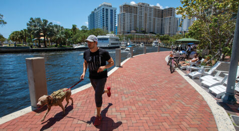 Man running with his dog along the New River at Riverwalk Fort Lauderdale in downtown Fort Lauderdale, Florida.