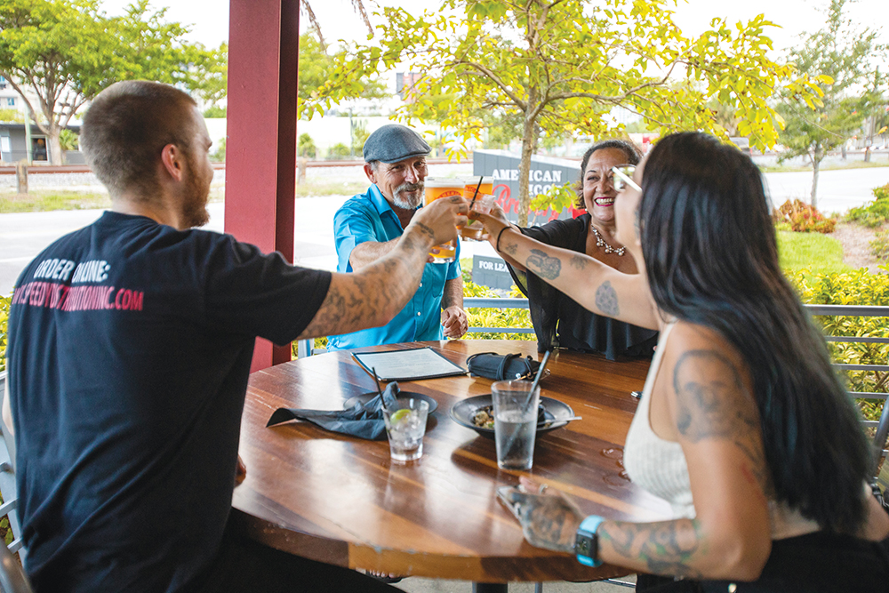 Group of people cheers their drinks at American Icon Brewery in Fort Lauderdale, FL
