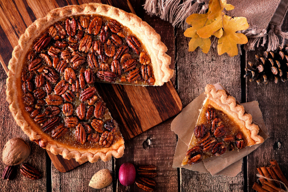Autumn pecan pie, overhead table scene with cut slice on a rustic wood background. South Carolina is home to a 17 stop Pecan Trail that is a must-visit during the fall.