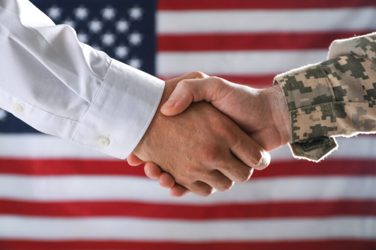 Soldier and businessman shaking hands against flag of USA, closeup