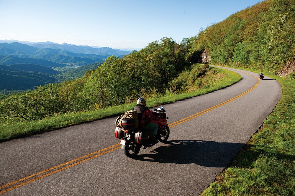 Cars and motorcycles drive along the Blue Ridge Parkway on top of Mt. Pisgah in North Carolina.