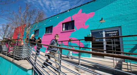 Visitos walk past the giant pink dog mural painted on the side of Pink Dog Creative in Asheville, North Carolina.