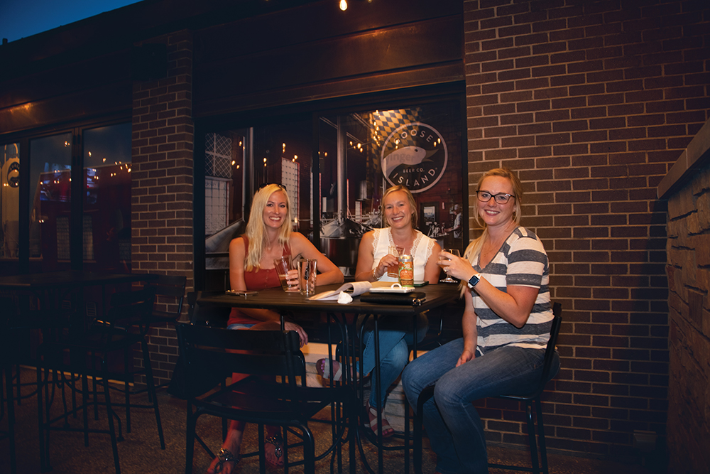 Women enjoy cocktails on the patio at the Brass Tap in the Cedar Valley region of Iowa.