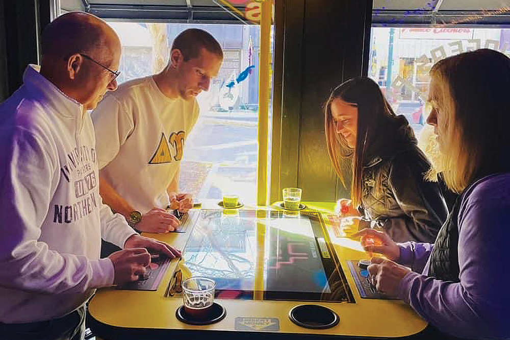 A family plays old school arcade games at Double Tap Beercade Cedar Falls, which is located in the Cedar Valley region of Iowa.