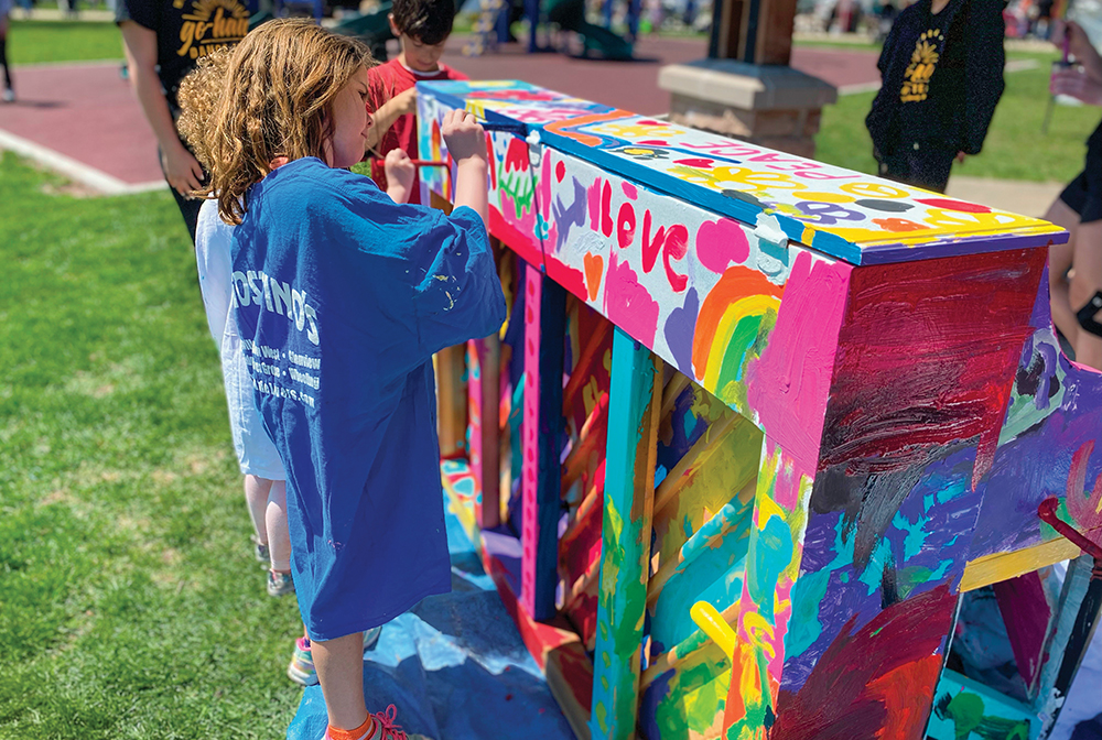 Little girl paints a park piano in the Cedar Valley region of Iowa.