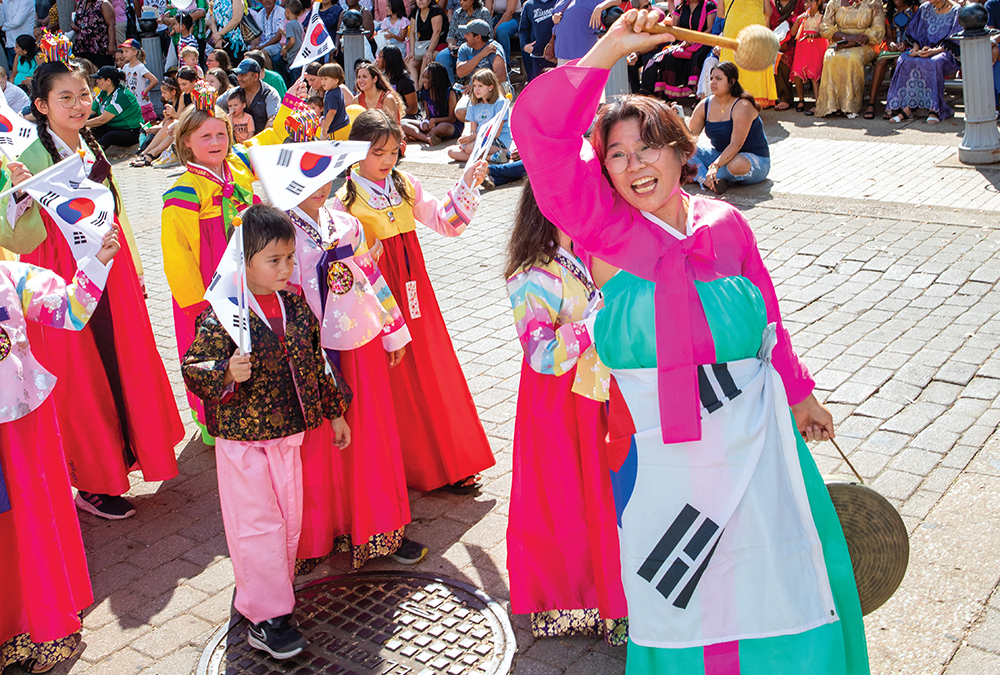 Sun Hwa Benard, right, walks with the South Korea delegation down Main Street during the Parade of Cultures at the start of the Jackson International Food and Arts Festival in downtown Jackson, TN.