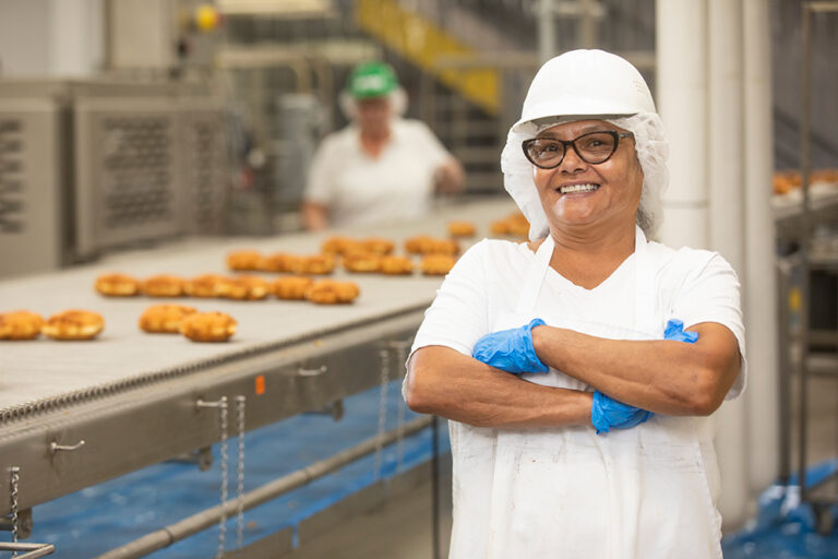 Person working the production line at Baker Boy in North Dakota. The wholesale baker is adding well-paying jobs to the state as it pioneers innovative manufacturing practices with new technologies, which are two of the largest industries and create several new jobs in North Dakota.