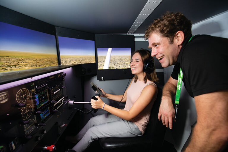 Emery Carter attempts to land a Cessna on the flight simulator as Keith Knoesel helps her at Eastern New Mexico University-Roswell.