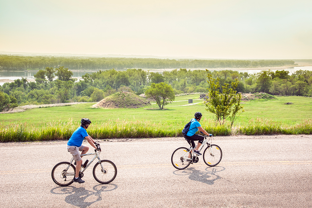 Men ride their bicycles along the trail at Fort Abraham Lincoln State Park in North Dakota.