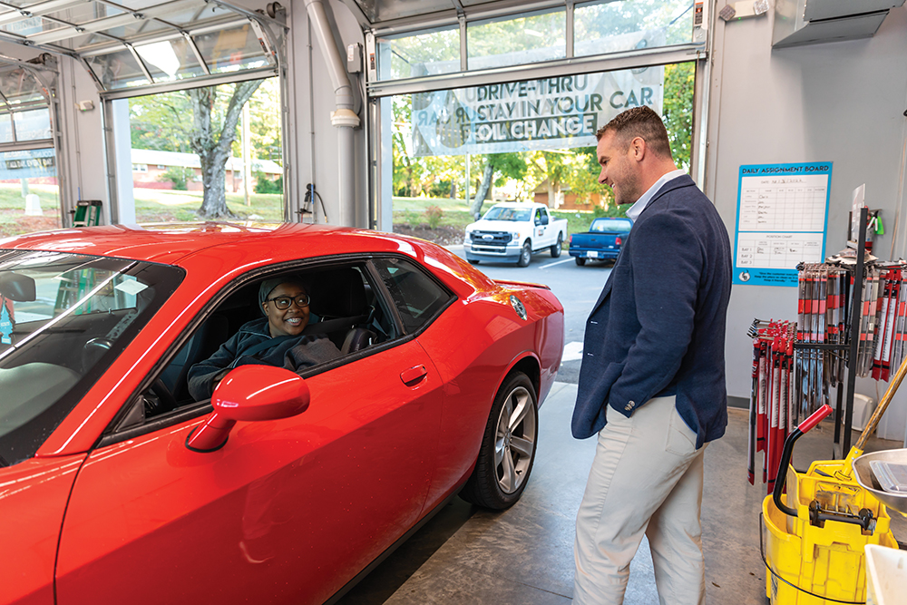 Winston Salem NC, Strickland Brothers, 10 minute oil change, 6061 University Parkway, CEO Justin Strickland talks with customer Tempestt Pettaway as her 2015 Dodge Challenger gets serviced.