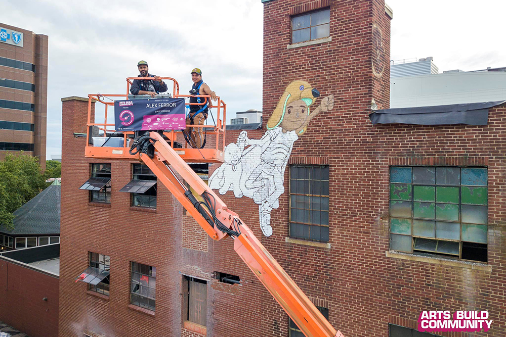 Artist Alex Ferror starts the second character for his mural. Stop by behind 1225 Elm Street and check it out. Photo Source_ Michael Cirelli @cirelliworks for Arts Build Community.