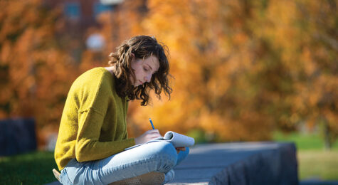 Student writes in a notebook on the University of Cincinnati campus in the Northern Kentucky region.
