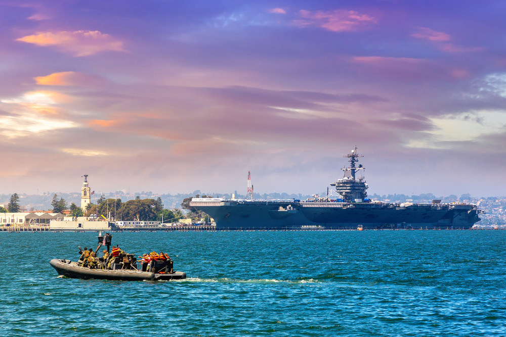 Naval Base navy guard boat patrol against modern nuclear aircraft carrier in San Diego, California, USA