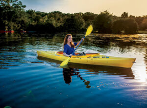 A woman kayaks on the Huron River/Gallup Park area in Ann Arbor, MI, where parks and trails are easily accessible. Home to the University of Michigan, Ann Arbor is a college town with a youthful vibe.